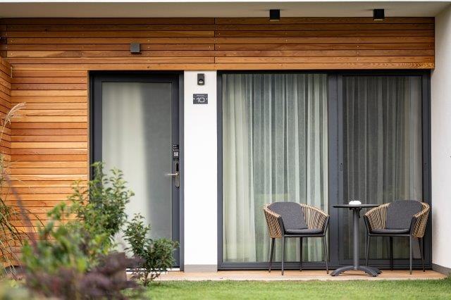 Das Gästehaus im Triad, © Marketing Platzhirsch, Gobauer Moderne Terrasse mit zwei Stühlen und einem Tisch vor einem Gästehaus.