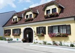 Simon, © Simon Johann Gelbes Gebäude mit braunem Dach und Blumenkästen an den Fenstern.