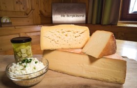 Hochwertige Produkte aus reinsten Rohstoffen, © Familie Ungersböck Verschiedene Käsesorten auf einem Holzbrett mit einem Glas eingelegtem Käse und einer Schüssel Frischkäse.