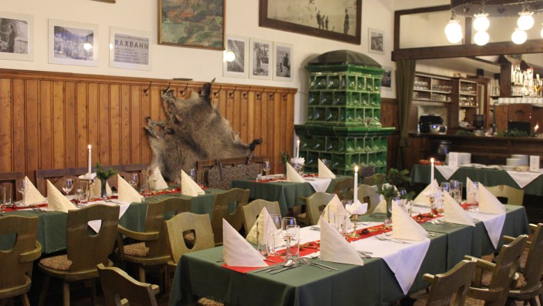 Interior view of the mountain inn, © Scharfgger´s Raxalpen Resort Cozy dining room with laid tables, wooden furniture and green tiled wall.