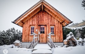Klammsauna, © TheVerve-Agentur (theverve.at) Eine kleine Holzhütte im Schnee mit einem steilen Dach und zwei Fenstern.