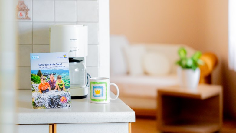 Herrenhaus Woltron, © Wiener Alpen / Christian Kremsl Küchenarbeitsplatte mit Broschüre, Kaffeetasse und Kaffeemaschine.