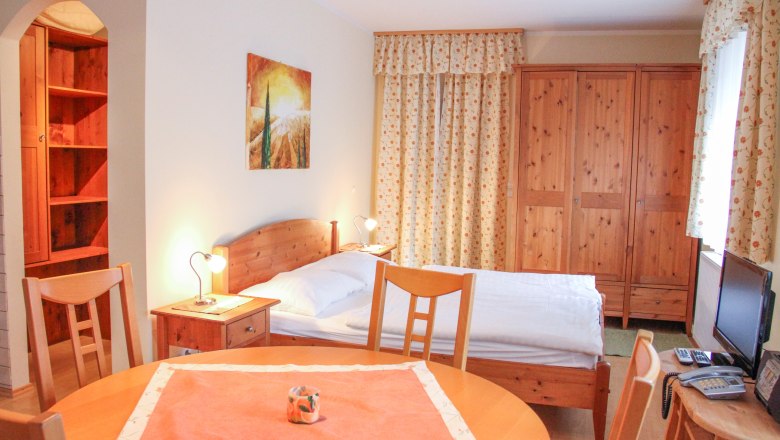 Wohnung 30m², © Haus Lenz Kleine Wohnung mit Holzmöbeln, Bett, Tisch und Schrank.