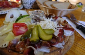 Symbolbild, © Pixapay Ein Holzbrett mit Aufschnitt, Käse, Tomaten, Gurken und Meerrettich. Im Hintergrund ein Brotkorb.