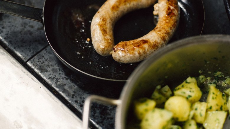 Hausgemachte Bratwurst, © Niederösterreich Werbung/Julius Hirtzberger Bratwurst in Pfanne mit Kartoffeln im Topf.
