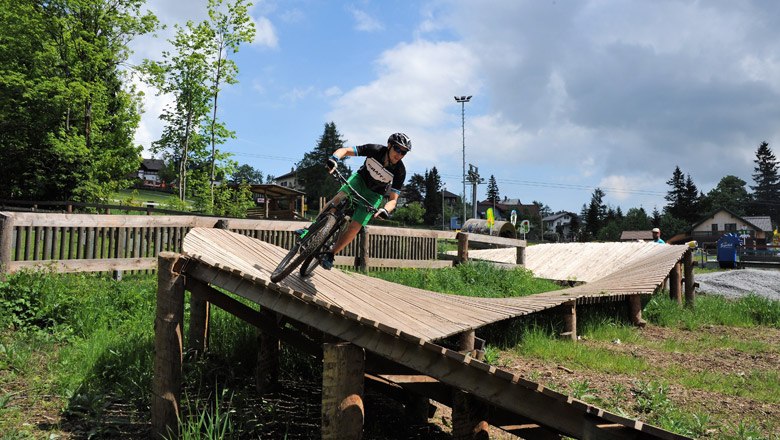Children's bike park Semmering, © Saskja Seidl Child riding on a wooden ramp in Bikepark Semmering.