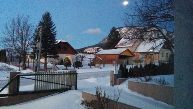 Winter - Zufahrt, © Reep Winterliche Landschaft mit schneebedeckten Häusern und Bäumen bei Dämmerung.