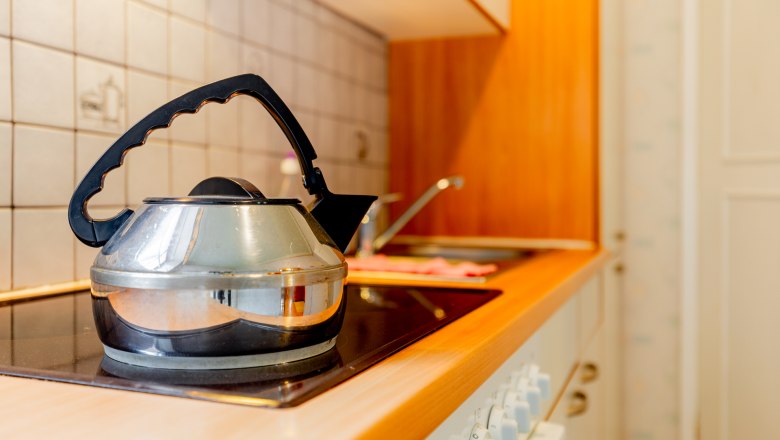Kitchen, © Wiener Alpen / Christian Kremsl A kettle stands on a stove in a kitchen with wooden elements and tiles.