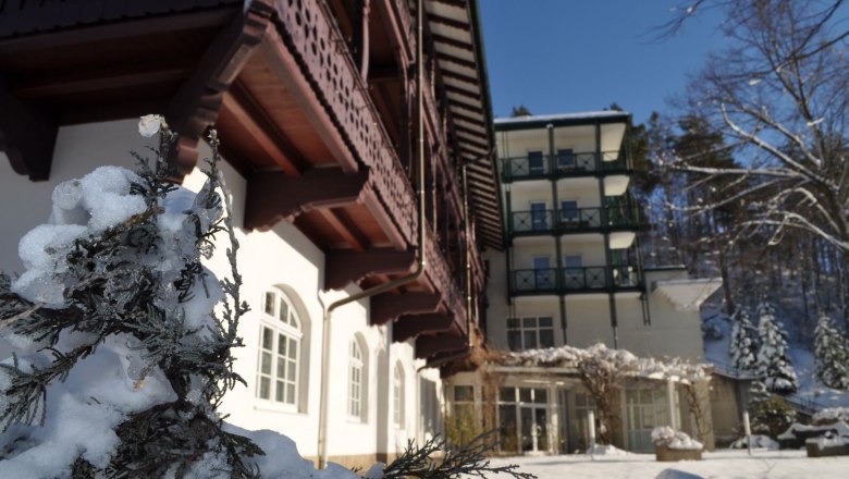 Schneeberghof im Winter, © Hotel Schneeberghof Winterliche Ansicht des Schneeberghofs mit Schnee bedeckten Pflanzen im Vordergrund.