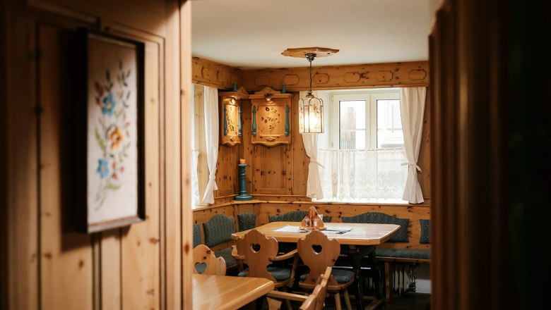 Stube im Raxalpenhof, © Sophie Menegaldo Gemütliche, rustikale Stube mit Holzmöbeln und dekorativen Elementen.