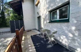 Ferienwohnung Detox, © Dekic-Ouaja Terrasse einer Ferienwohnung mit Tisch und Stühlen, umgeben von Bäumen.