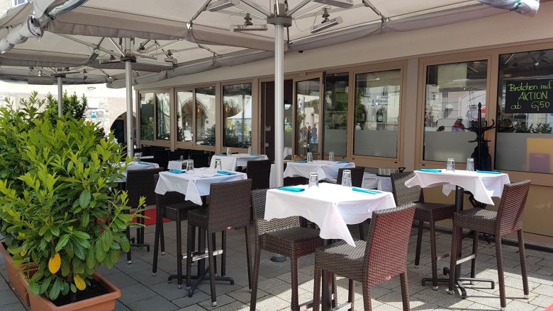 Reef & Beef im Sommer, © Piroska Weiss Außenbereich eines Restaurants mit gedeckten Tischen und Sonnenschirmen.