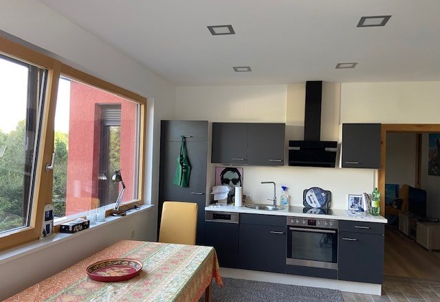 Fully equipped kitchen, © Wiener Alpen Modern kitchen with gray cabinets, stove, sink and table with colorful tablecloth.