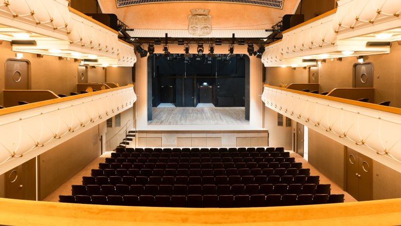 Prunkvoller Zuschauerraum: Wo Kultur auf bernsteinfarbenen Sitzreihen glänzt, © Alex Schwarz Photography Innenansicht des prachtvollen Stadttheaters Wiener Neustadt mit goldgelben Samtsesseln, Logen und funkelndem Kronleuchter