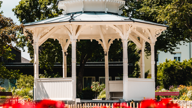 Pavillon Stadtpark, © Busy Shutters Weißer Pavillon vor blühenden roten Blumen