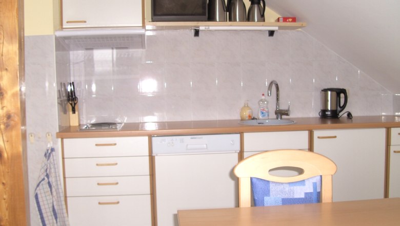 Kueche im Frühstücksraum, © Reep Kleine Küche mit weißen Schränken, Spüle, Wasserkocher und Kaffeemaschinen auf einem Regal.