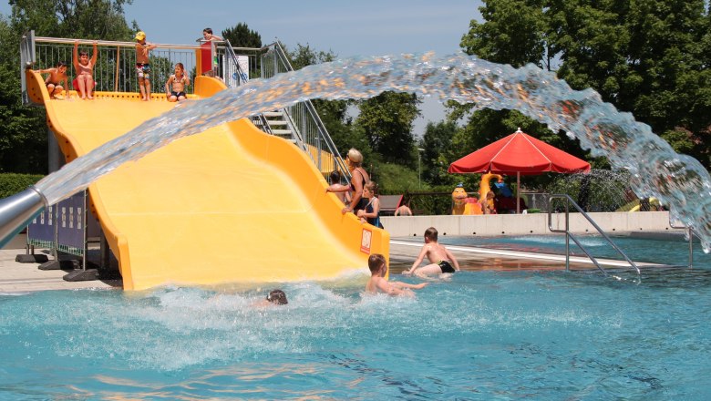 Erholungszentrum Neunkirchen, © StadtgemeindeNeunkirchen Kinder spielen auf einer gelben Wasserrutsche in einem Freibad.