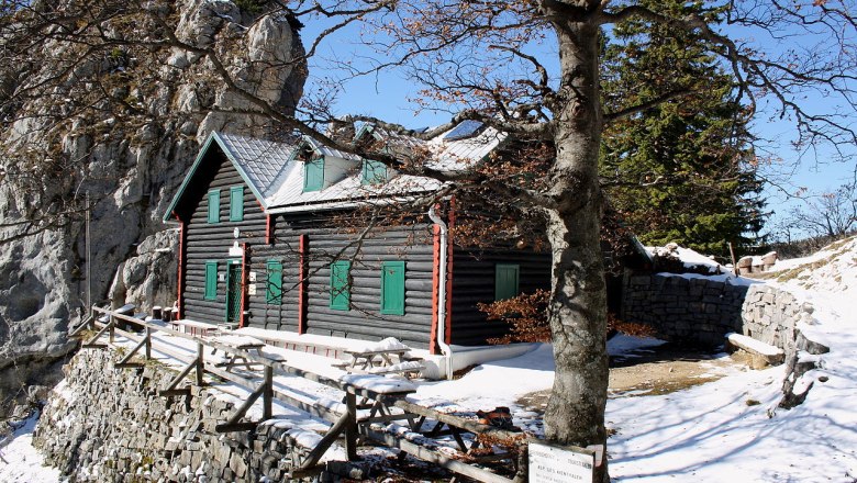 Kienthalerhütte, © BwagCommons Eine Berghütte aus Holz mit grünen Fensterläden, umgeben von Schnee und Felsen, unter einem klaren blauen Himmel.