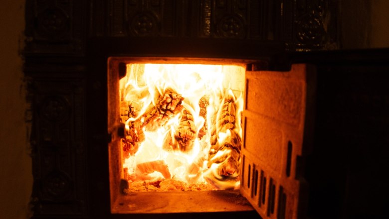 Orlet an der Rax, © Sofia Orlet Ein brennender Kamin mit sichtbaren Flammen und Holzscheiten.