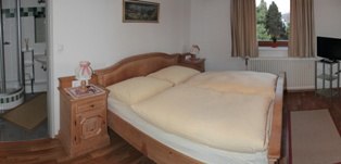 Guest room, © Michael Muehlendorfer Cozy guest room with double bed, bedside table and window with curtains.