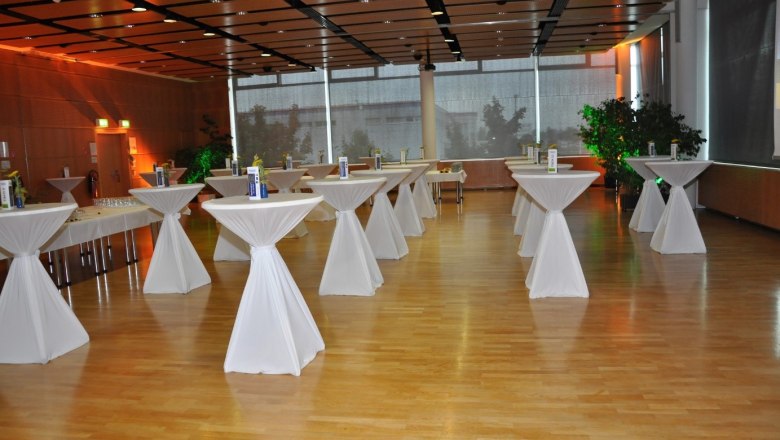 TFZ, © TFZ An empty event room with bar tables covered with white tablecloths.