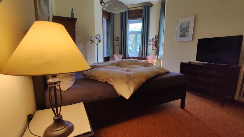 Villa Petterhof, © Villa Petterhof Gemütliches Schlafzimmer mit Doppelbett, Nachttischlampe, Fenster und Fernseher.