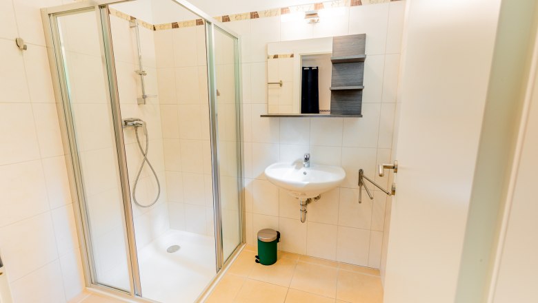 Dusche, © Wiener Alpen / Christian Kremsl Modernes Badezimmer mit Duschkabine, Waschbecken und Spiegel.