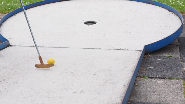 Minigolf, © gemeinfrei Minigolfbahn mit Schläger und gelbem Ball vor einem Loch.