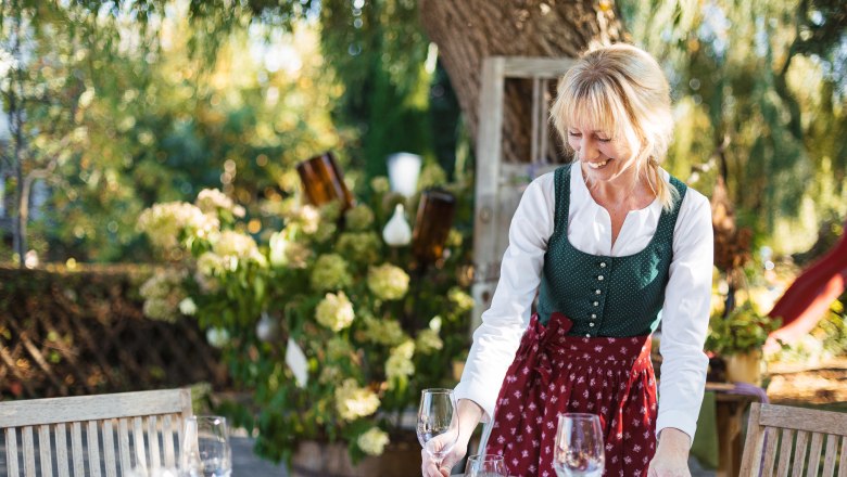 Karin Ottner warmly welcomes hungry day trippers, © Niederösterreich Werbung/Mara Hohla Woman in traditional dress sets a table outdoors.