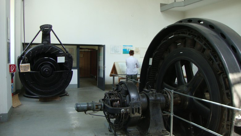 EVN Schaukraftwerk Turbinen, © EVN Innenansicht eines Schaukraftwerks mit großen Turbinen und einer Person, die eine Informationstafel liest.