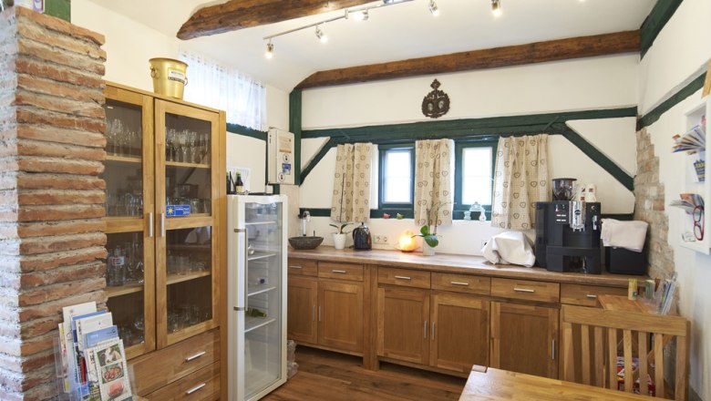 Breakfast room, Victoria guest room, © Marianne Graf A cozy breakfast room with wooden furniture, a fridge, a coffee machine and decorative wooden beams on the ceiling.