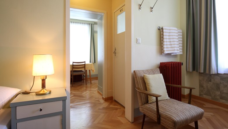 Übernachten im Looshaus., © Christian Redtenbacher Innenansicht eines Zimmers im Looshaus mit Sessel, Nachttischlampe und Tisch im Hintergrund.