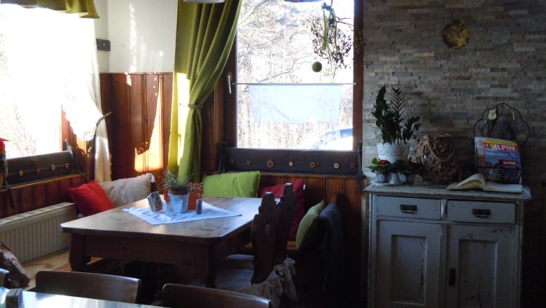 ..ein gemütliches Amiente., © Waxeneckhaus Gemütliche Ecke in einem Raum mit Holztisch, Kissen und Pflanzen.