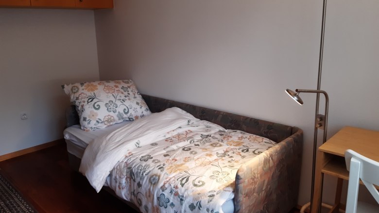 Zimmer 2 - Zusatzbett für eine Person, © Kainz-Waldinger Ein kleines Zimmer mit einem Einzelbett, einem Schreibtisch mit Lampe und einem Stuhl. Das Bett hat eine bunte Blumenbettwäsche.