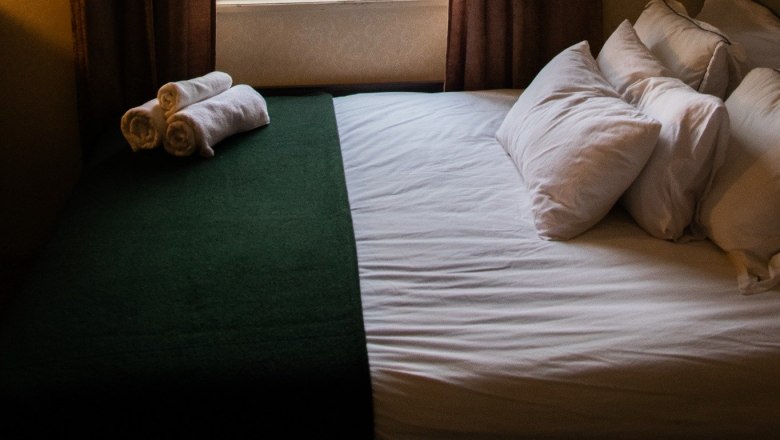 Orlet an der Rax, © Sofia Orlet Ein gemütliches Schlafzimmer mit einem Bett, das vor einem Fenster steht. Draußen sind Bäume und ein Hausdach zu sehen.