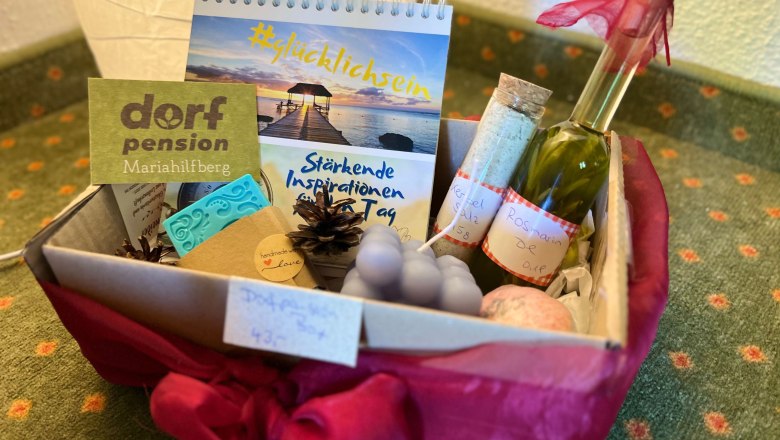 Wohlfühlkorb, © Dorfschmiede eG Ein Geschenkkorb mit verschiedenen Wellness-Produkten, darunter ein Kalender, eine Flasche Öl und handgemachte Seifen.