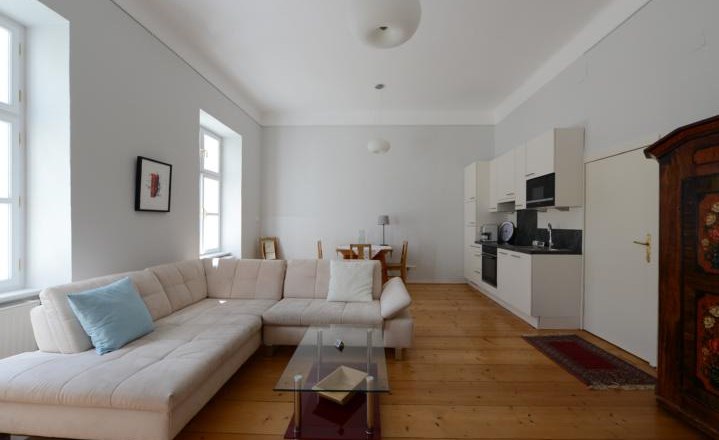 Apartment G2 im Gerhardthof Reichenau, © Gerhardthof Reichenau Helles Wohnzimmer mit Ecksofa, Glastisch, Esstisch und Küchenzeile.