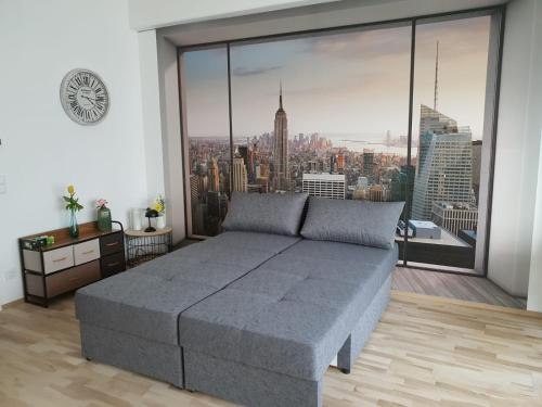 Green Point Apartments, © Green Point Apartments Zimmer mit grauem Sofa und Fototapete von New York Skyline.