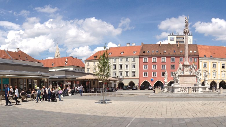 Hauptplatz mit Marienmarkt Panorama, © Stadt Wiener Neustadt Michael Weller Panoramablick auf einen belebten Hauptplatz mit historischen Gebäuden und einer Statue in der Mitte.