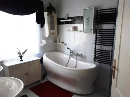 Bathroom with bathtub, © bed and pool Modern bathroom with free-standing bathtub, white tiling, black towel rail and red carpet.