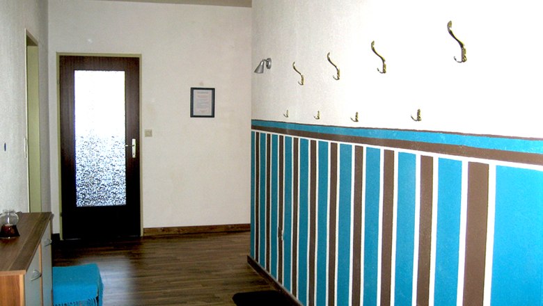 Hallway, © Anke Spreitzer Hallway with wooden floor, colorful wall design and coat hooks.