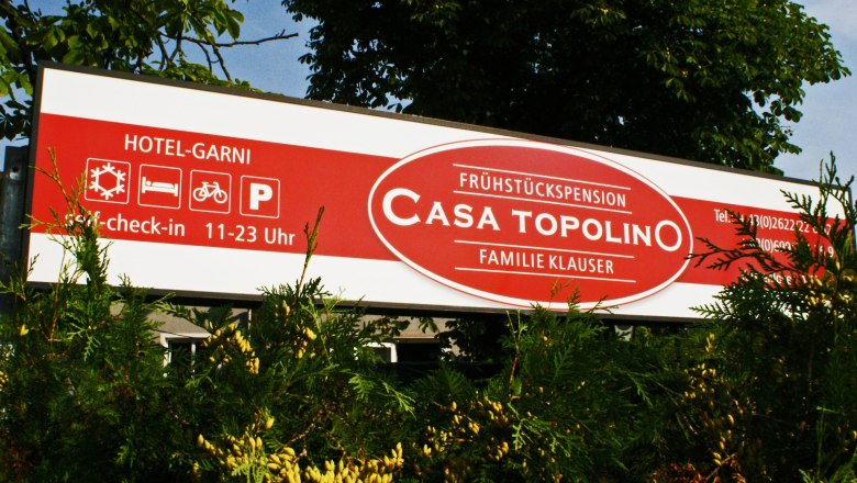 Schild der Frühstückspension Casa Topolino mit Kontaktinformationen und Öffnungszeiten.