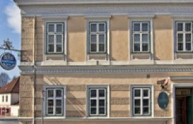 Fassade eines zweistöckigen Gebäudes mit mehreren Fenstern und einem Schild mit der Aufschrift 'Gasthof Pension Manhalter'.