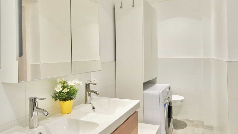 Modern bathroom with double washbasin, mirror, washing machine and WC.