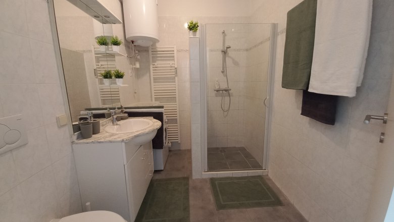 Modernes Badezimmer mit Dusche, Waschbecken, Spiegel und Handt&uuml;chern.