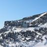 Winterlandschaft mit dem Ottohaus auf einem verschneiten Berg unter klarem Himmel.