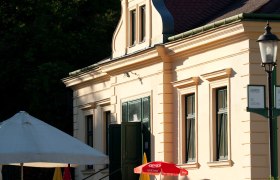 Außenansicht eines Restaurants mit Sonnenschirmen und Gästen im Freien.