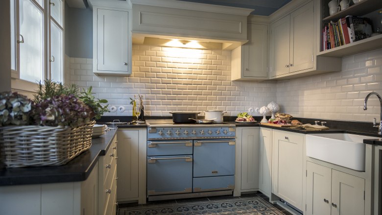 Elegant kitchen with blue oven, white cupboards and tiles.