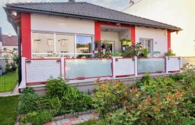grau rotes Haus mit Balkon und Blumen