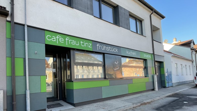 Exterior view of the Frau Tinz caf&eacute; with green and gray fa&ccedil;ade.